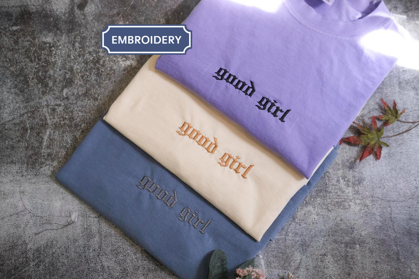 three t-shirts with the text "Good girl" embroidered on them, arranged in a stack.