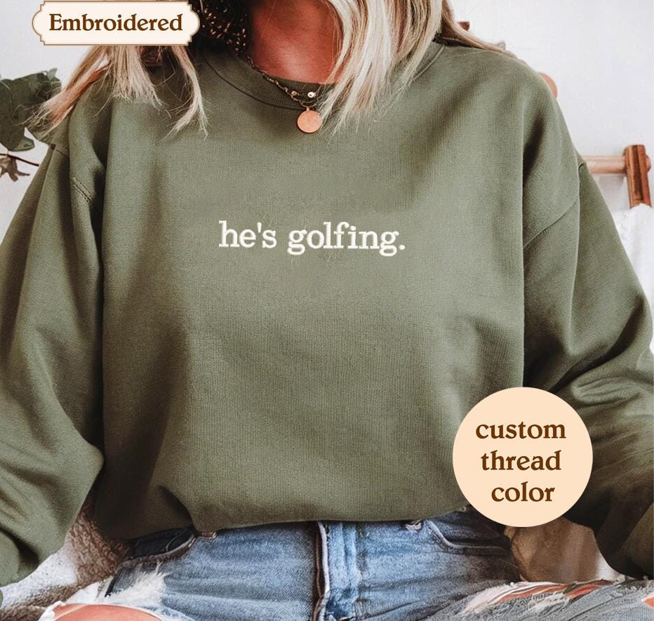 a woman wearing a sweatshirt that says he's golfing