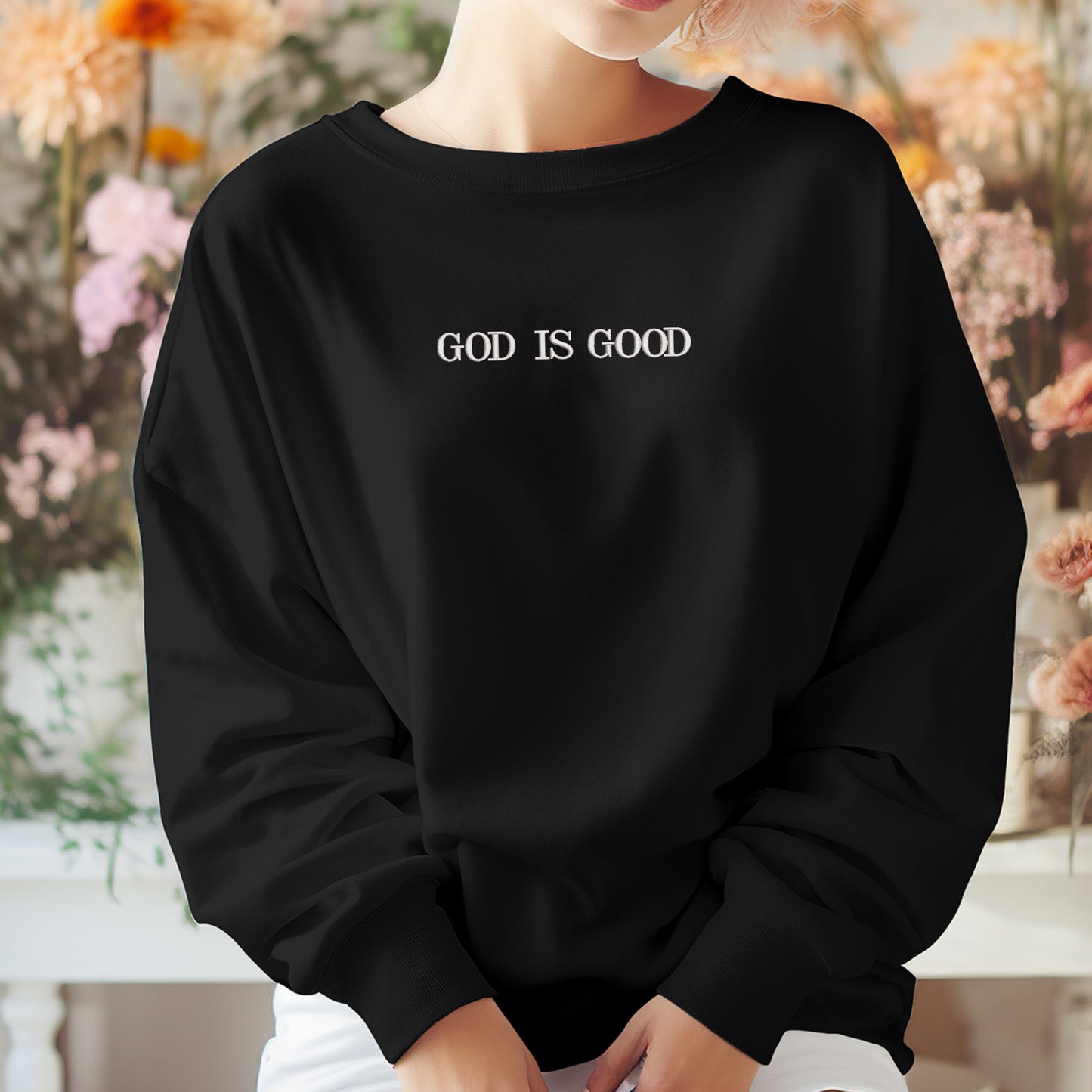 A person wearing a black sweatshirt with the text "GOD IS GOOD" printed on it.