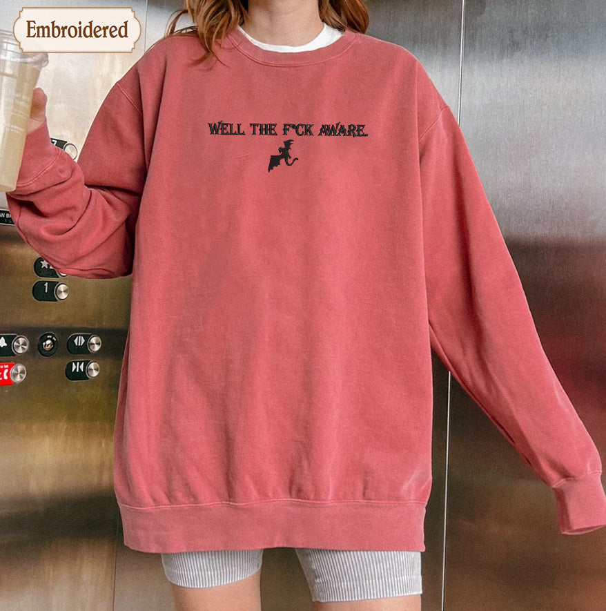 A person wearing a red sweatshirt with the text "WELL THE F*C K AWARE" printed on it.