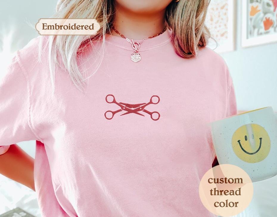 a woman wearing a pink shirt with scissors on it
