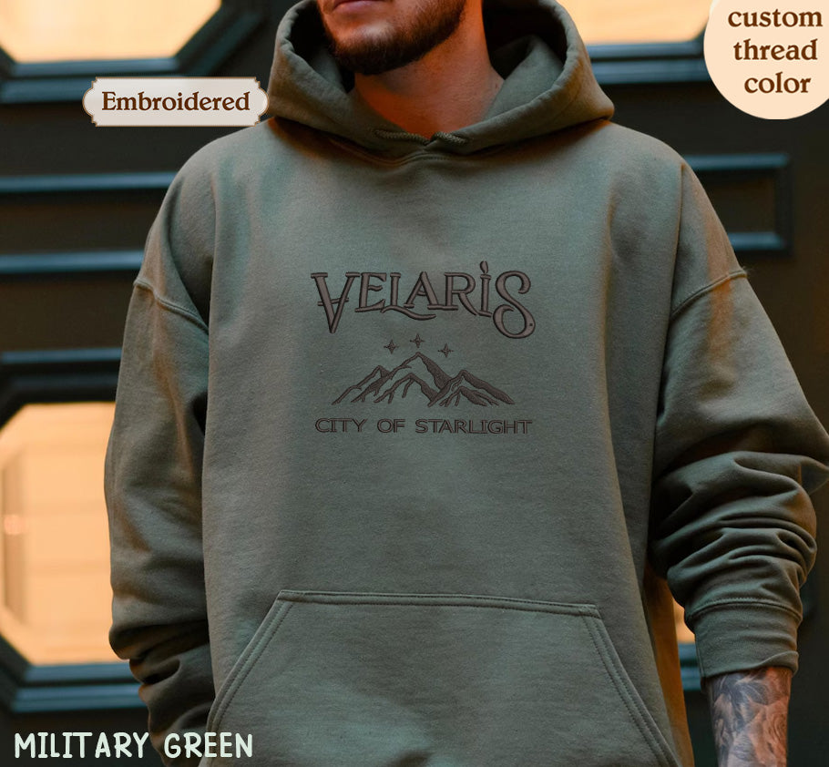 A person wearing a green hoodie with the text "VELARI'S CITY OF STARLIGHT" printed on it.