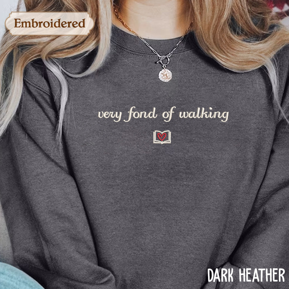 A person wearing a gray sweatshirt with the text "very fond of walking" embroidered on it.