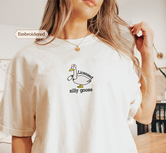 A woman wearing a white t-shirt with a cartoon duck and the text "Licensed silly goose" printed on it.