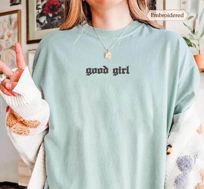 a woman wearing a green shirt with the words good girl written on it