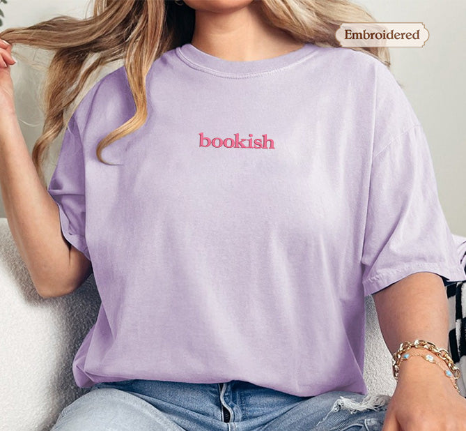 A person wearing a purple t-shirt with the word "bookish" printed on it.