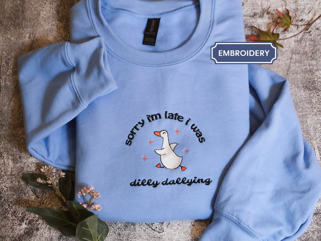 A light blue sweatshirt with a humorous text and graphic design printed on it.