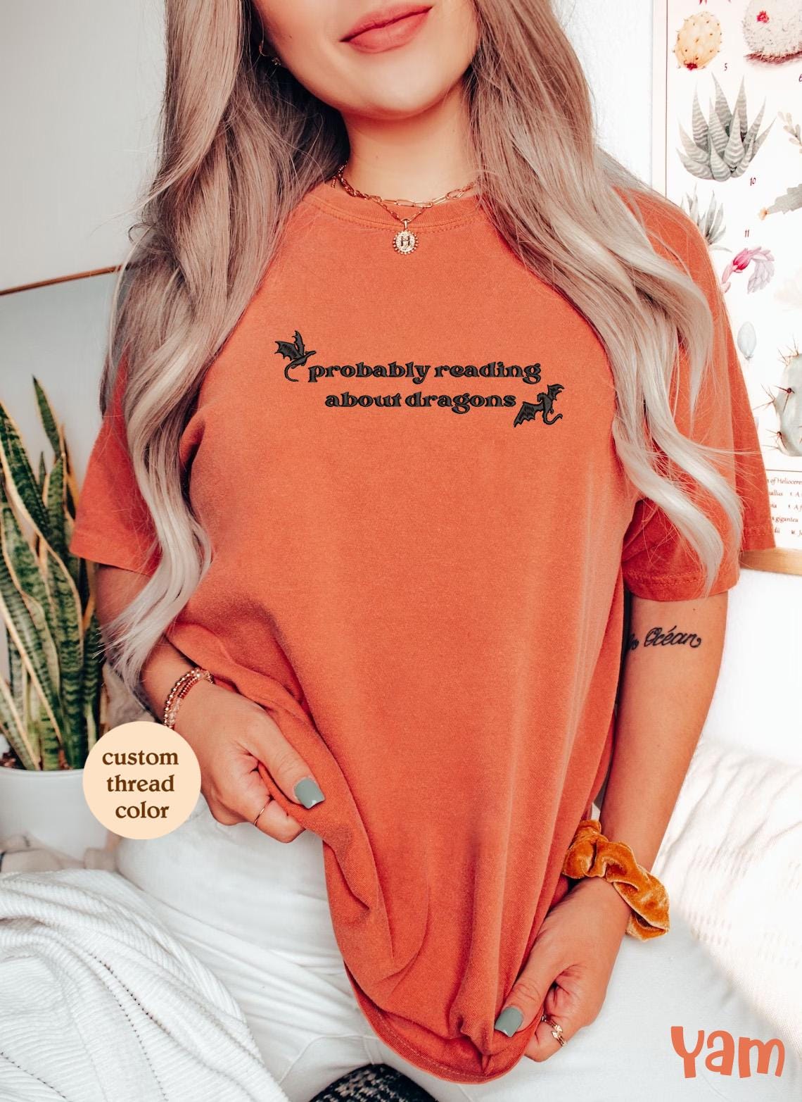 a woman wearing an orange tshirt with a black and white dog on it