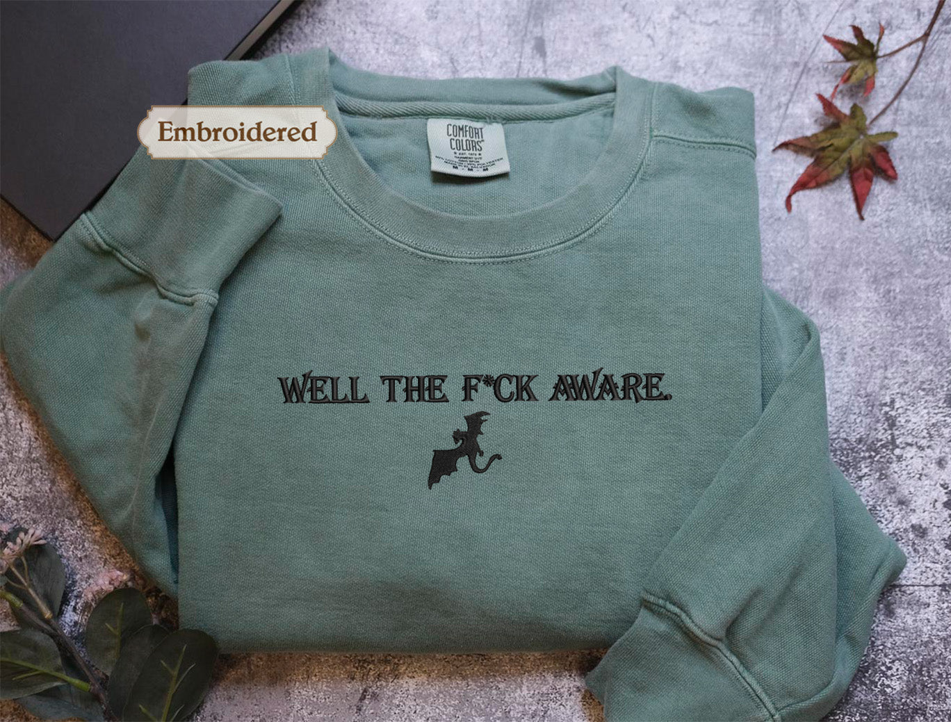 a green long-sleeved shirt with the text "WELL THE F*CK AWARE" printed on it.