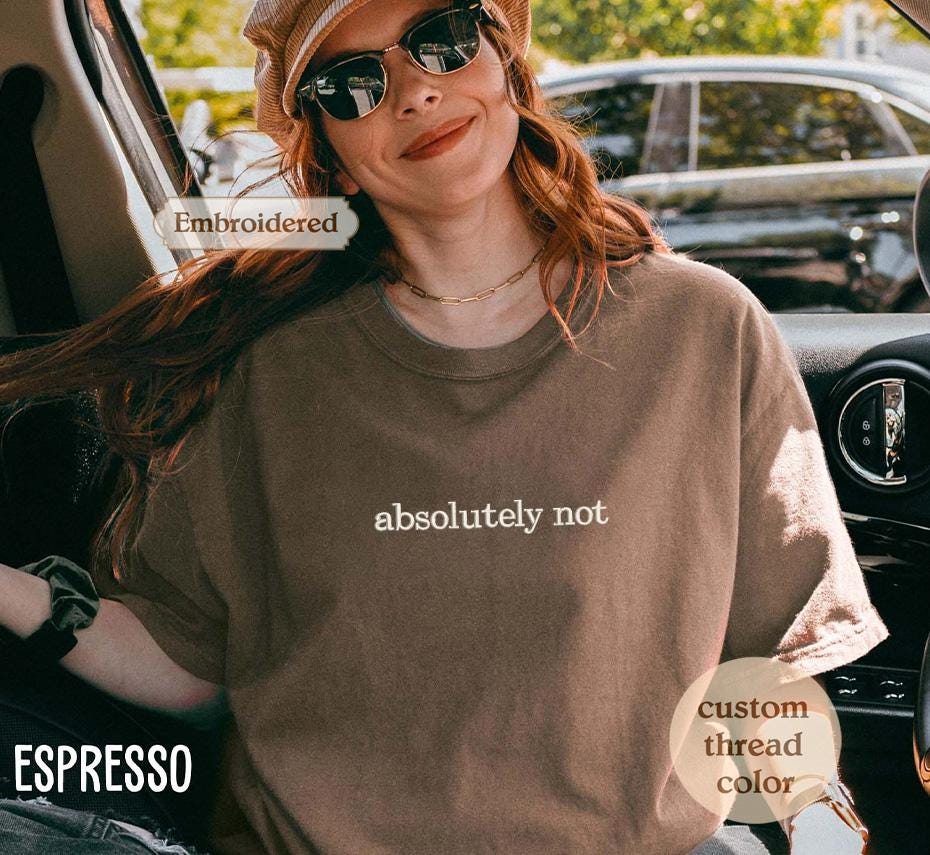 a woman sitting in a car wearing a t - shirt that says absolutely not