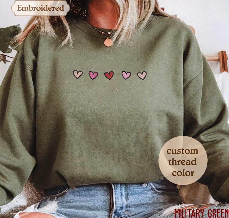 a woman wearing a green sweatshirt with hearts embroidered on it