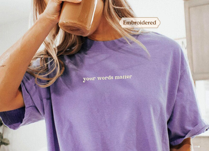 A person wearing a purple t-shirt with the text "your words matter" printed on it.