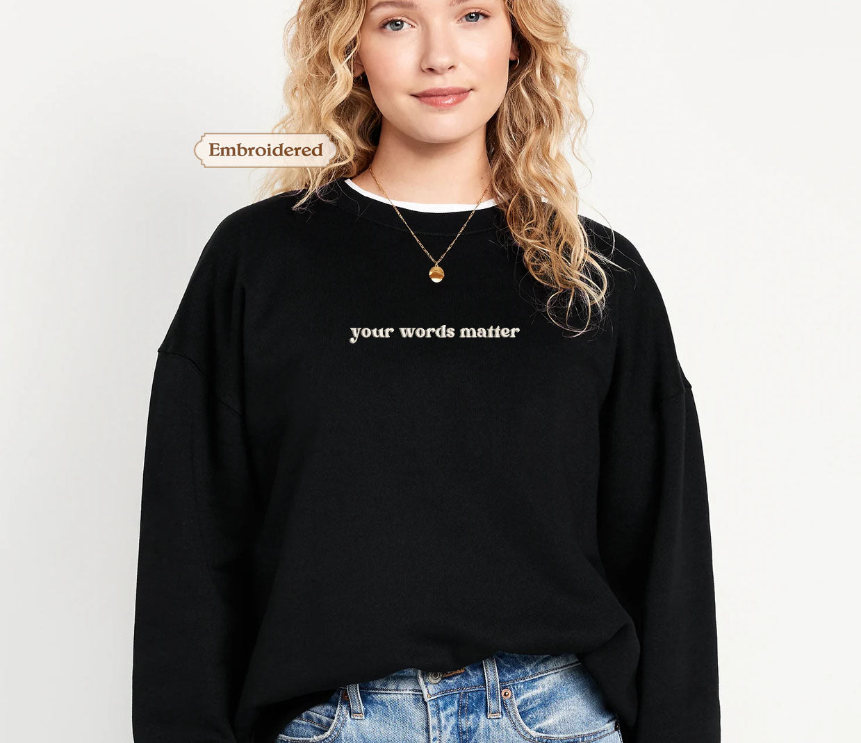 A woman wearing a black sweater with the text "your words matter" embroidered on it.
