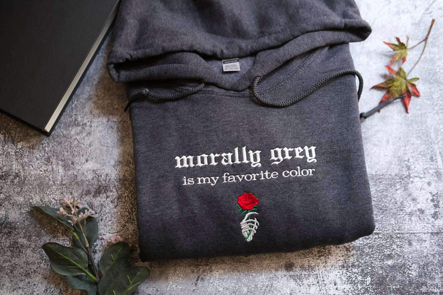 a gray hoodie with the text "morally grey is my favorite color" and a rose graphic, along with a skeleton hand embroidered on the front.