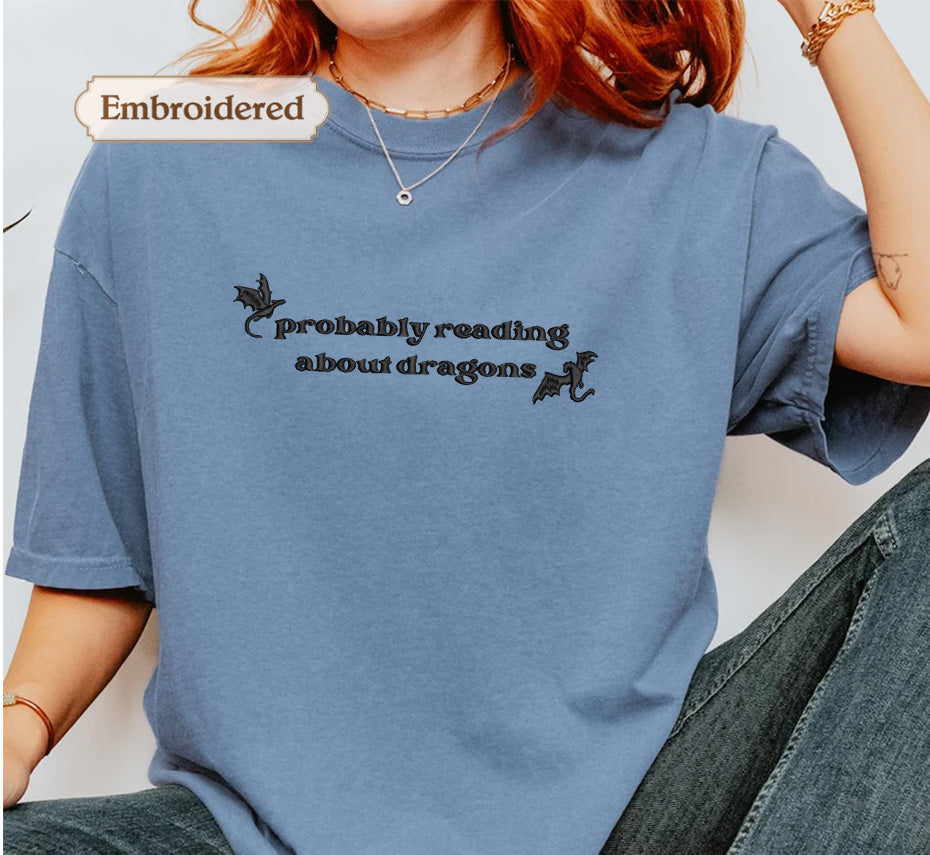 A person wearing a blue t-shirt with the text "probably reading about dragons" printed on it.