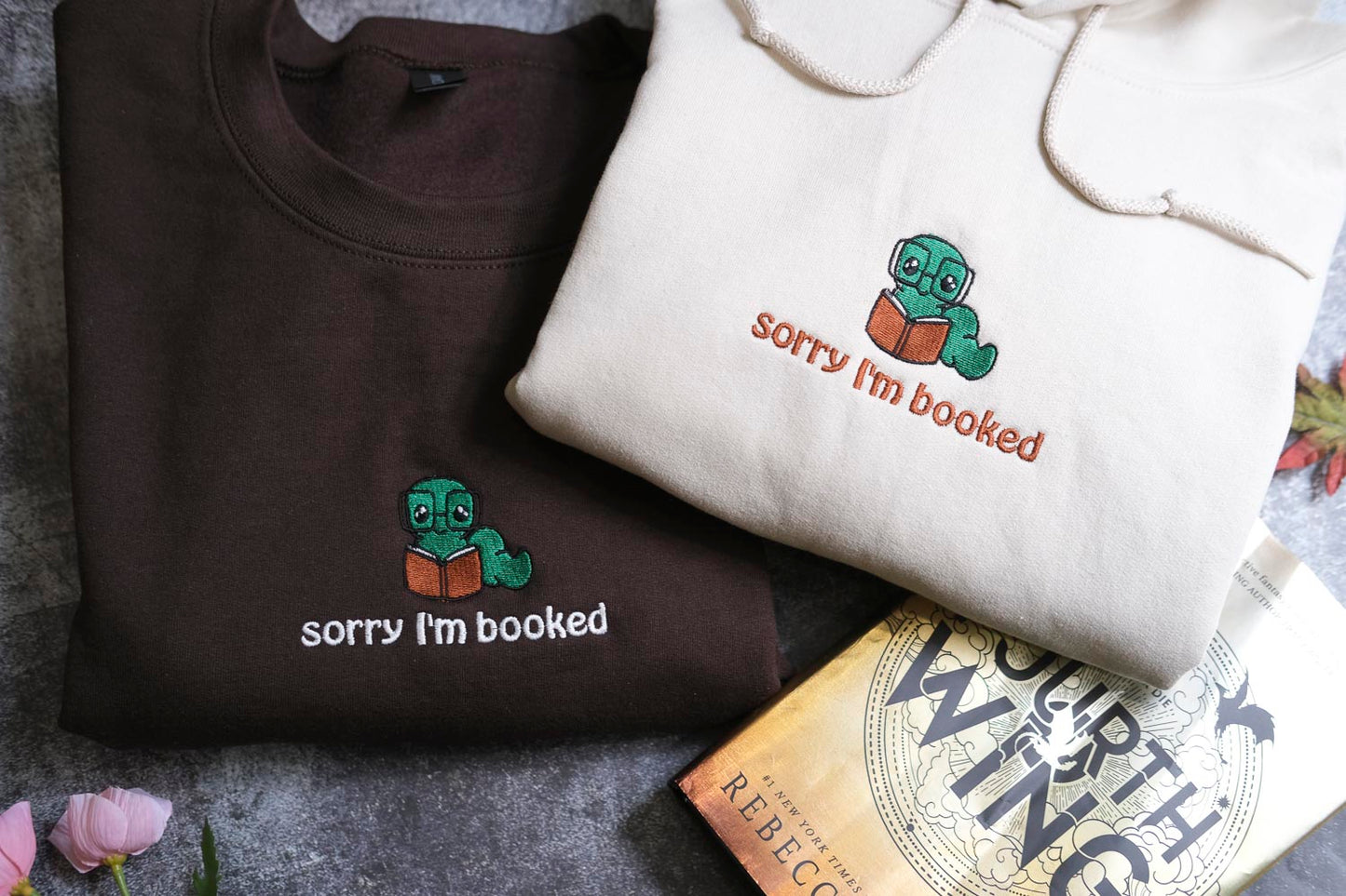 two t-shirts with a humorous text and a book titled "The Deathly Wings" on a table.