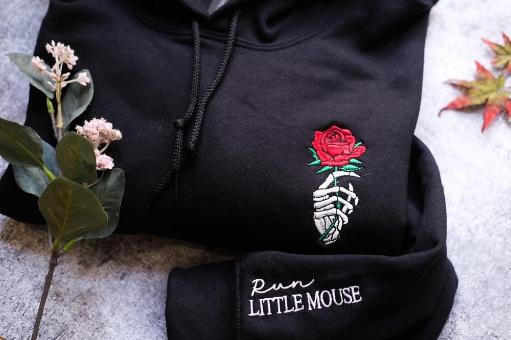 a black hoodie with a rose embroidered on it