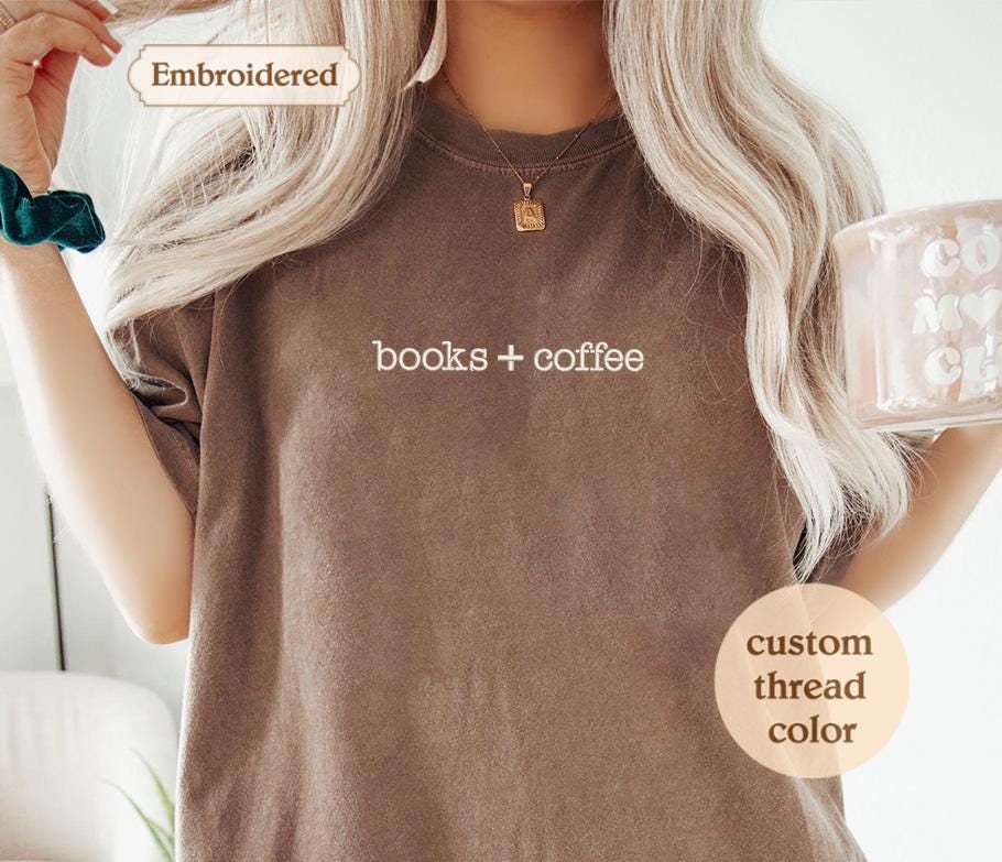 a woman holding a cup of coffee and wearing a t - shirt