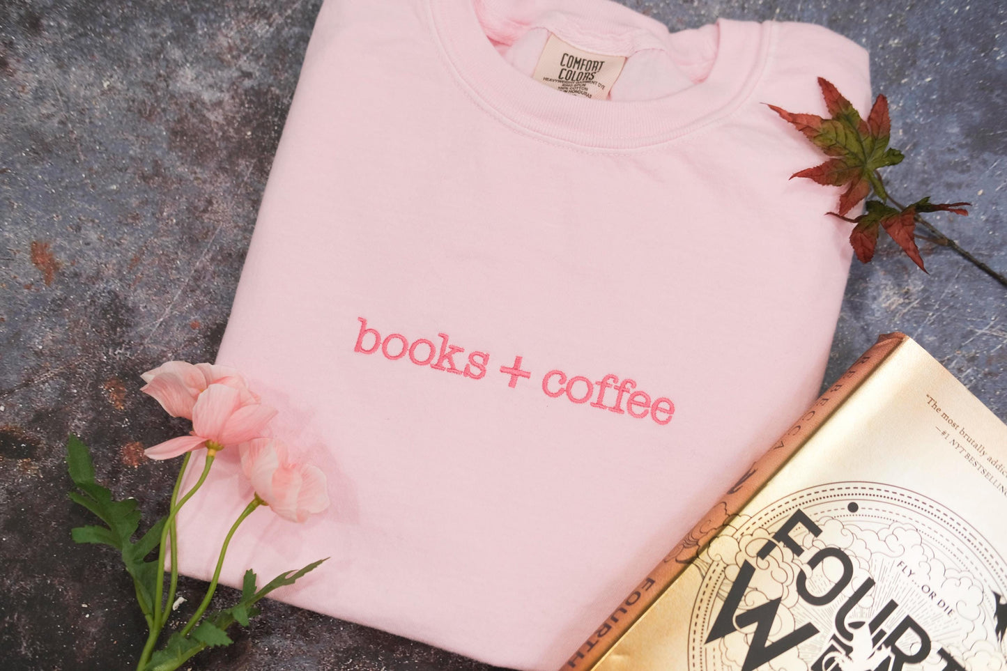 a pink t - shirt that says coffee + cookies next to a book