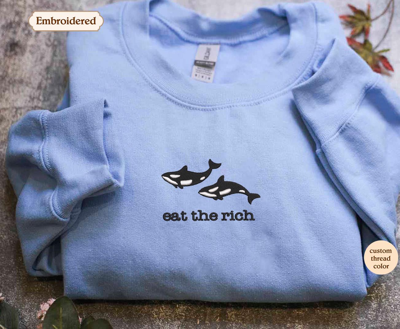 a blue t - shirt with an orca whale saying eat the rich