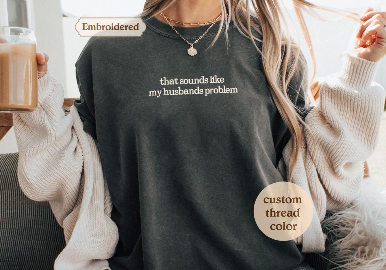 a woman holding a cup of coffee and wearing a long sleeved shirt