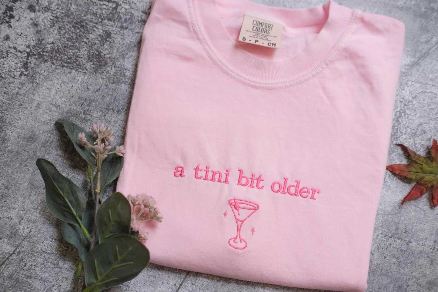 a pink shirt that says a tint bit older