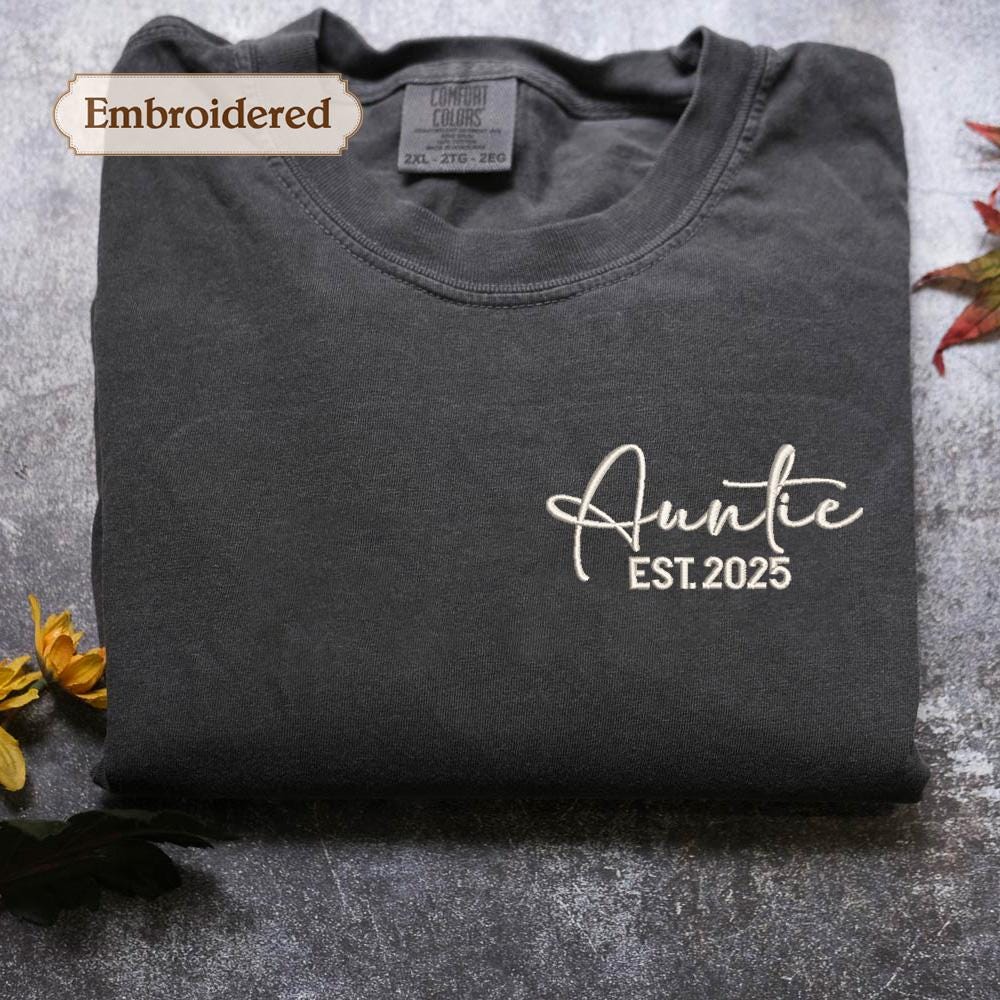 a gray t-shirt with the text "Auntie EST. 2025" embroidered on it, along with a label indicating it is "Embroidered" and "Comfortable Colors".