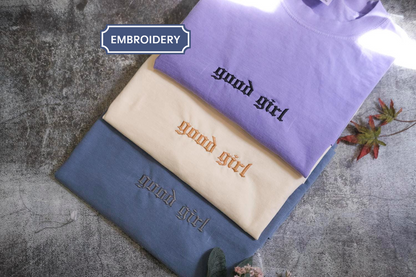three t-shirts with the text "Good girl" embroidered on them, arranged in a stack.