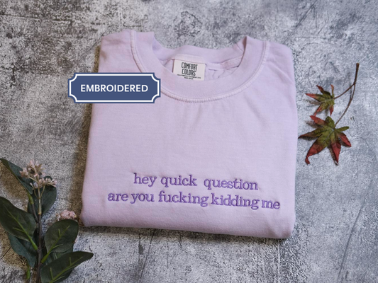 a purple t-shirt with the text "hey quick question are you fucking Kiddin Me" printed on it, along with some leaves and flowers.
