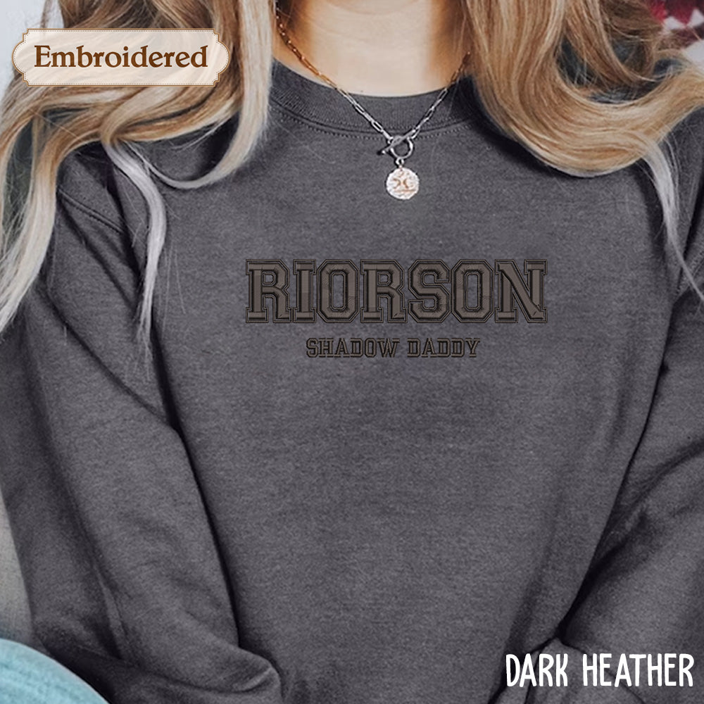 A close-up of a person wearing a gray sweatshirt with the text "RIOSON SHADOW DADDY" printed on it.