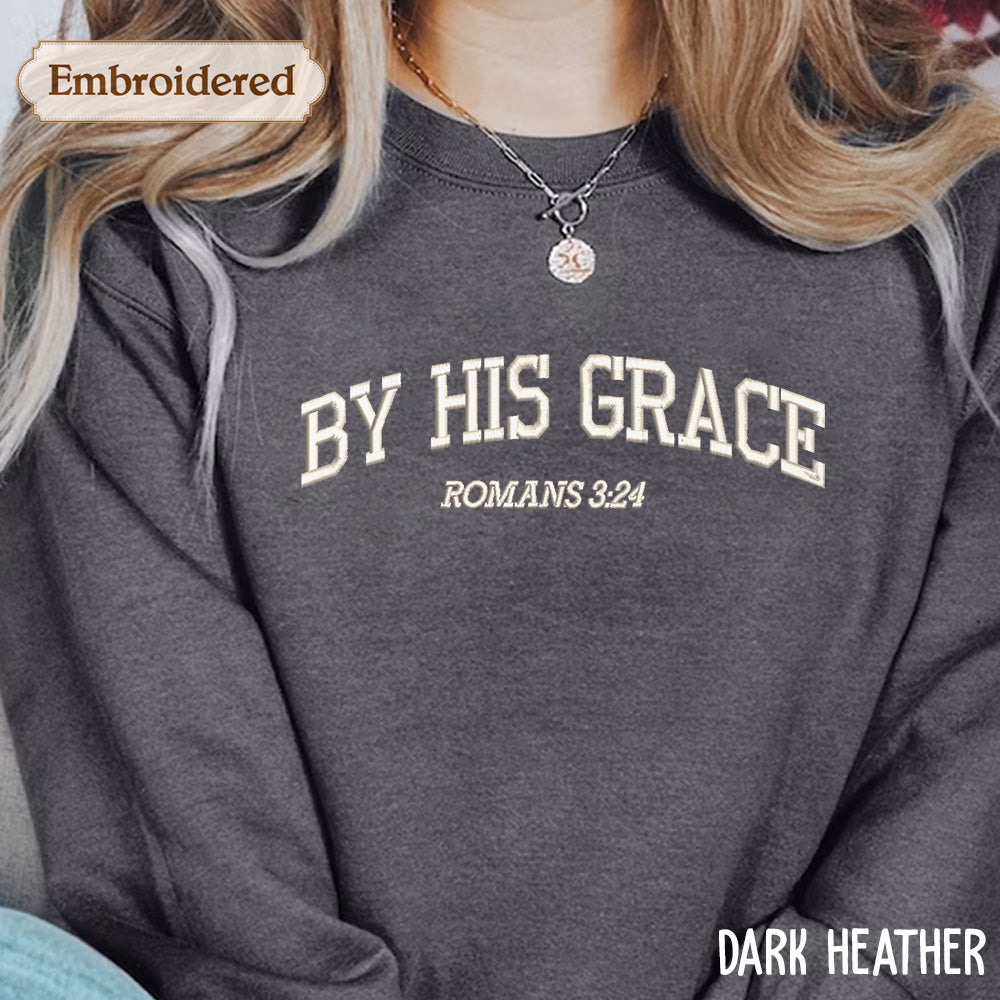 A close-up of a person wearing a gray sweatshirt with the text "BY HIS GRACE ROMANS 3:24" embroidered on it.