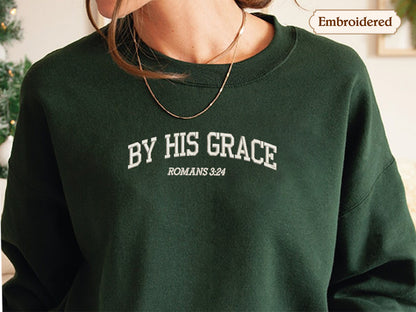 A person wearing a green sweatshirt with the text "BY HIS GRACE ROMANS 3.24" embroidered on it.