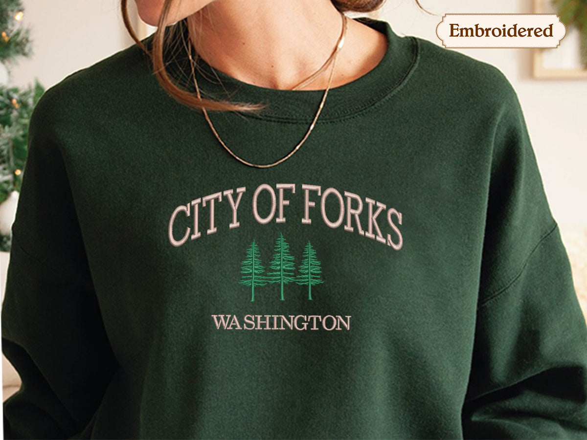 A person wearing a green sweater with the text "CITY OF FORKS WASHINGTON" embroidered on it.