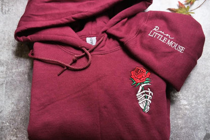 a red hoodie with a rose embroidered on it