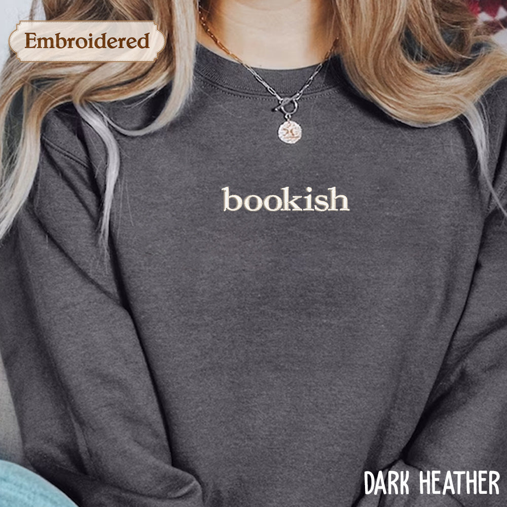 A person wearing a gray sweatshirt with the word "bookish" printed on it.