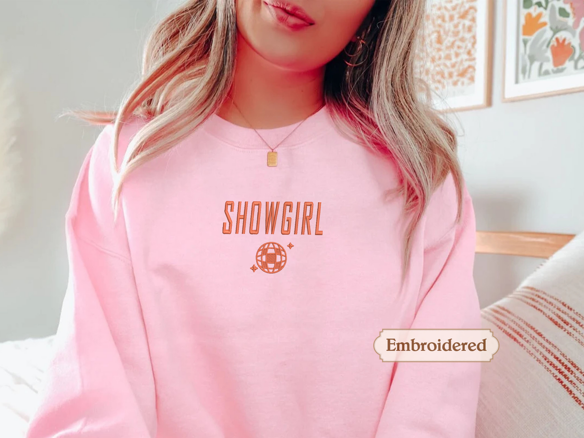 A woman wearing a pink sweatshirt with the word "SHOWGIRL" printed on it.
