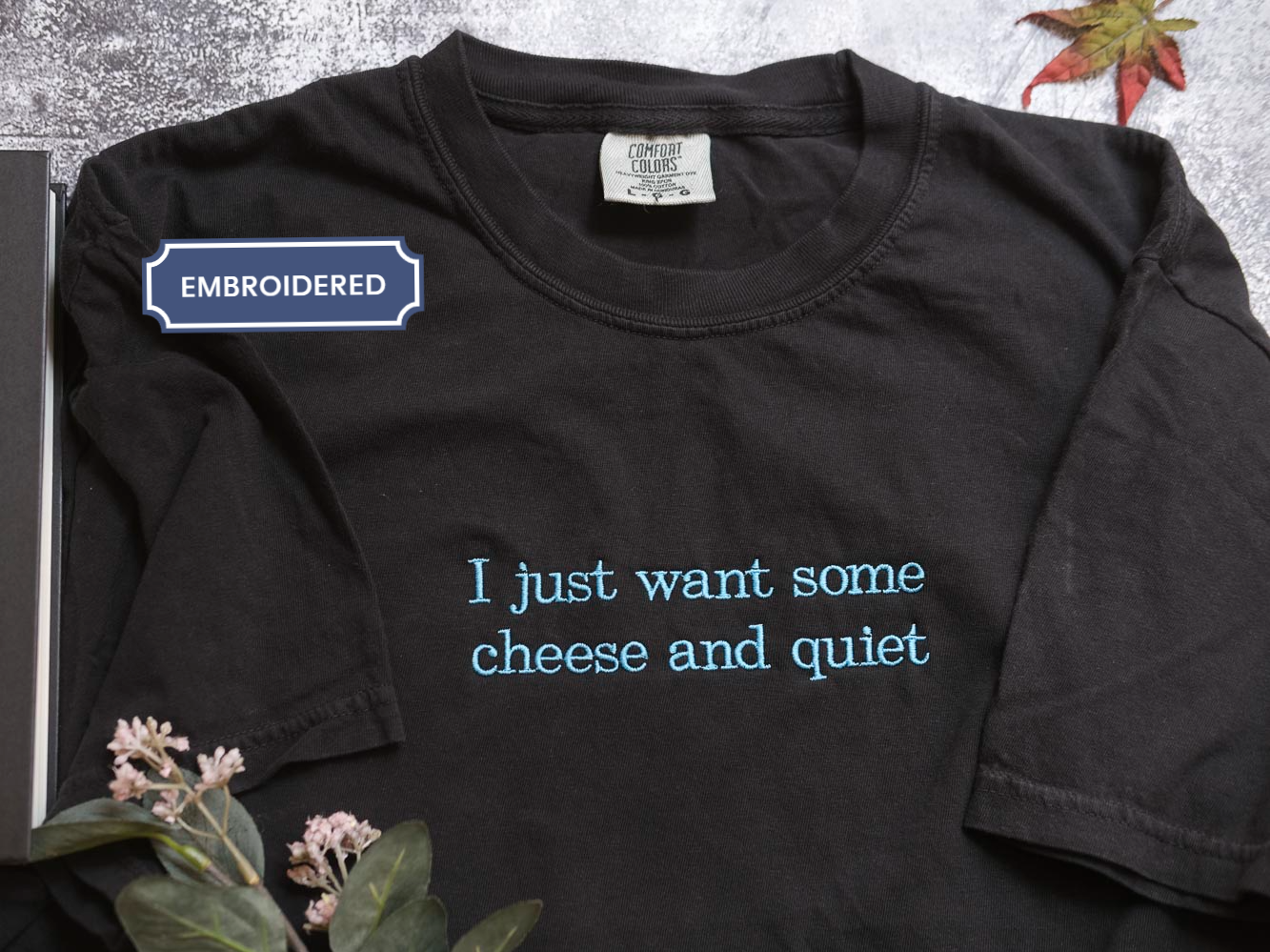 a black t-shirt with a humorous text printed on it, which reads "I just want some cheese and quiet".