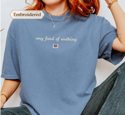 A person wearing a blue t-shirt with the text "very fond of walking" printed on it.