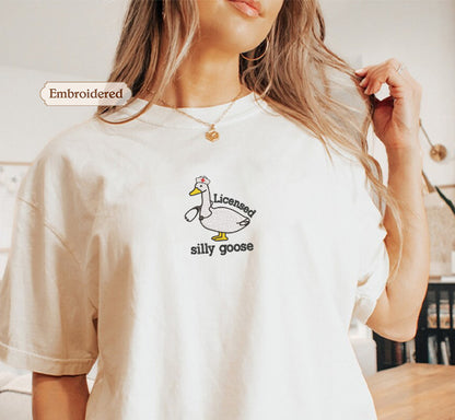 A woman wearing a white t-shirt with a cartoon duck and the text "Licensed silly goose" printed on it.