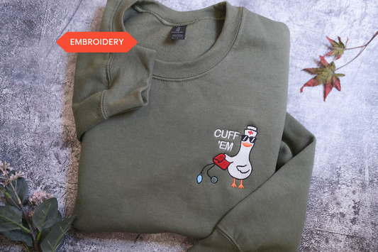 A green sweatshirt with a cartoon duck and the text "CUFF 'EM" printed on it, along with a small red heart symbol.