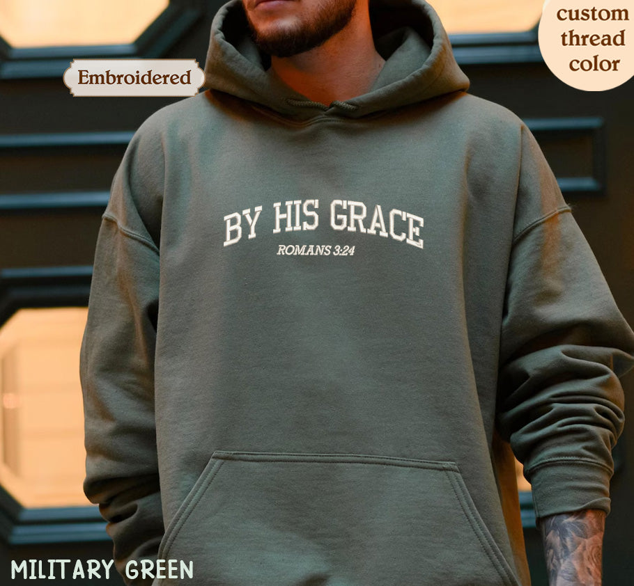 A person wearing a green hoodie with the text "BY HIS GRACE ROMANS 824" printed on it.