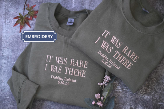 two gray sweatshirts with white text printed on them, placed on a gray surface.