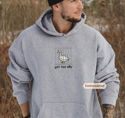 a man wearing a grey hoodie with a duck on it
