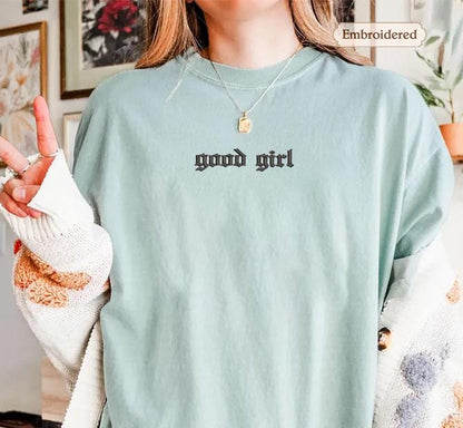 a woman wearing a green shirt with the words good girl written on it
