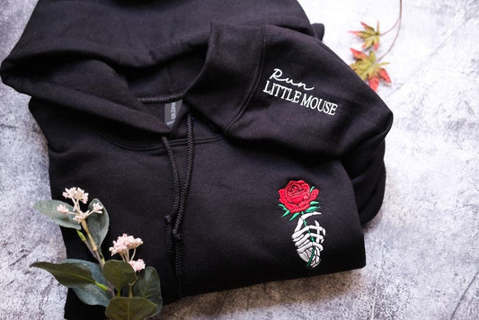 a black hoodie with a rose embroidered on it