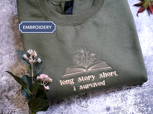 A green t-shirt with a printed design and text, along with some flowers and leaves, on a textured surface.