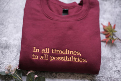A maroon t-shirt with the text "In all timelines, in all possibilities" printed on it, along with a small leaf and a plant.