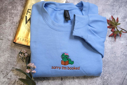 a blue sweatshirt with a cartoon character and text, along with a book and some flowers.