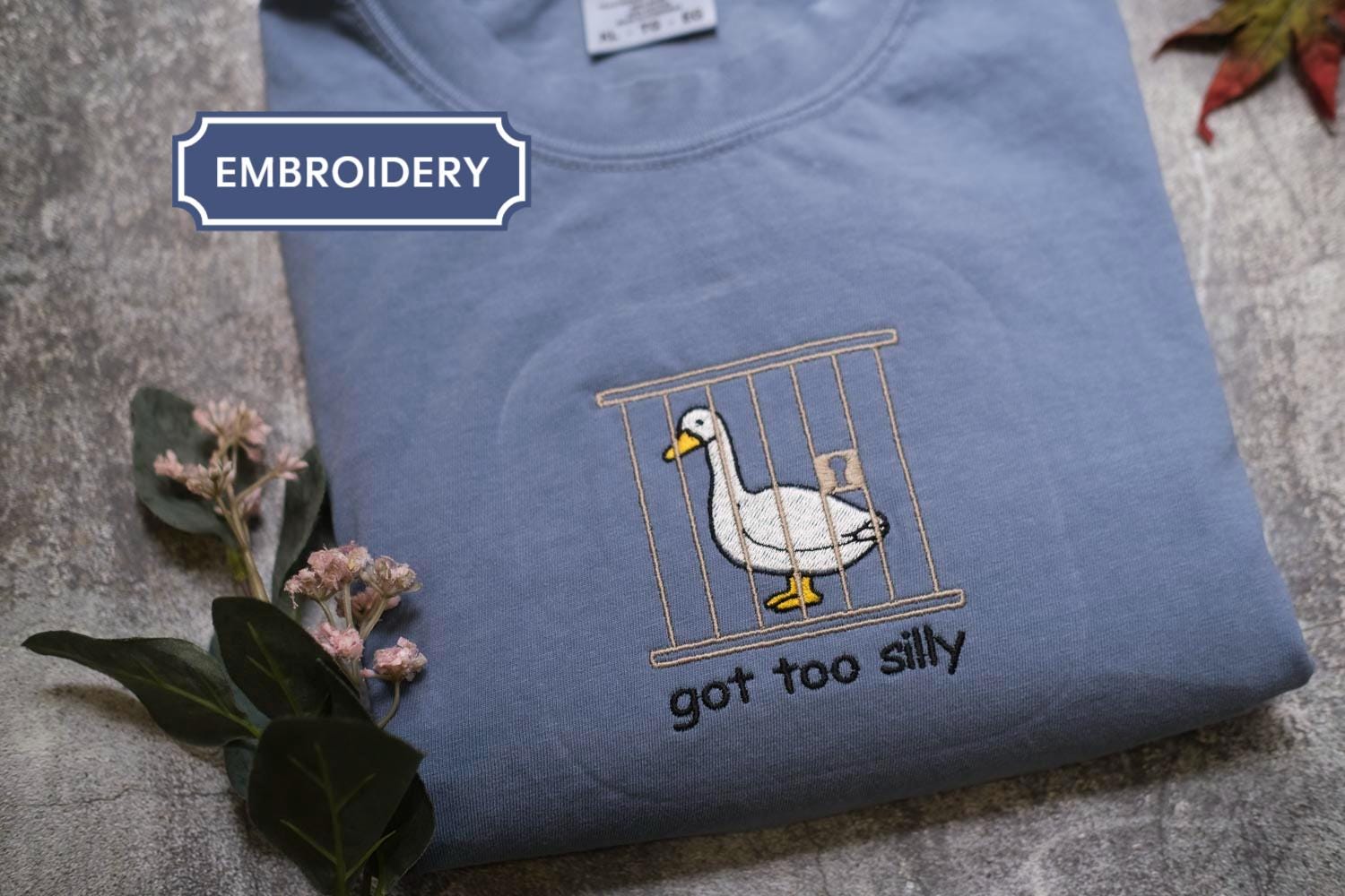 A blue t-shirt with a cartoon duck inside a cage and the text &quot;got too silly&quot; below the image.