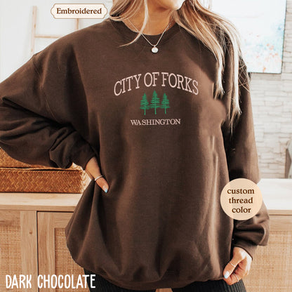 A woman wearing a brown sweatshirt with the text "CITY OF FORKS WASHINGTON" printed on it.
